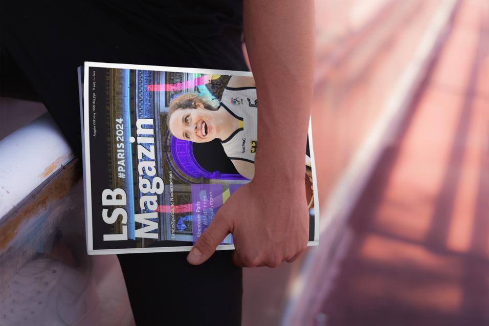 Eine Person h&auml;lt ein Magazin mit der Aufschrift &bdquo;LSB Magazin&ldquo; in der N&auml;he einer Laufbahn. Hintergrund unscharf.